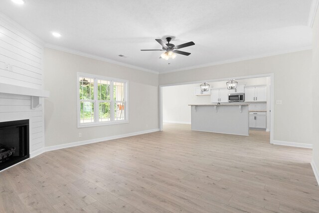 unfurnished living room with crown molding, ceiling fan, a fireplace, and light hardwood / wood-style flooring