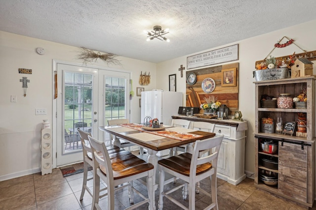 tiled dining room featuring french doors and a textured ceiling