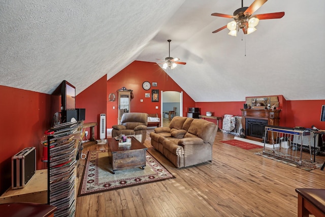 living room featuring ceiling fan, lofted ceiling, hardwood / wood-style floors, and a textured ceiling