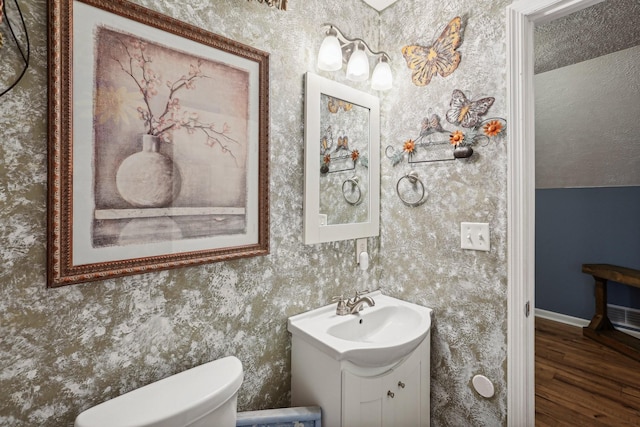 bathroom featuring vanity, hardwood / wood-style floors, lofted ceiling, and toilet