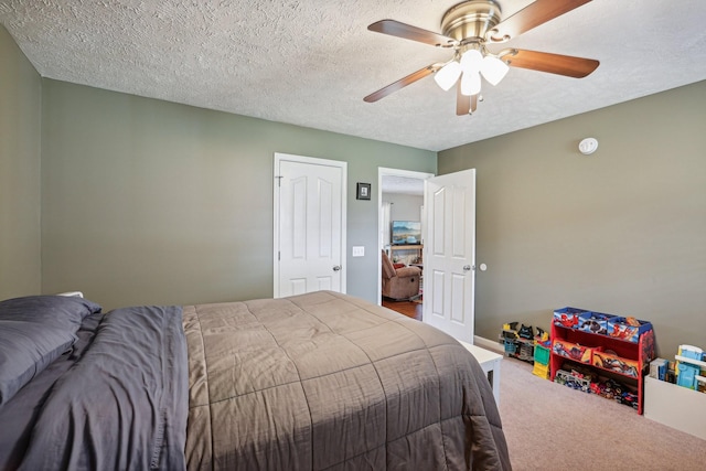 bedroom with ceiling fan, carpet floors, and a textured ceiling