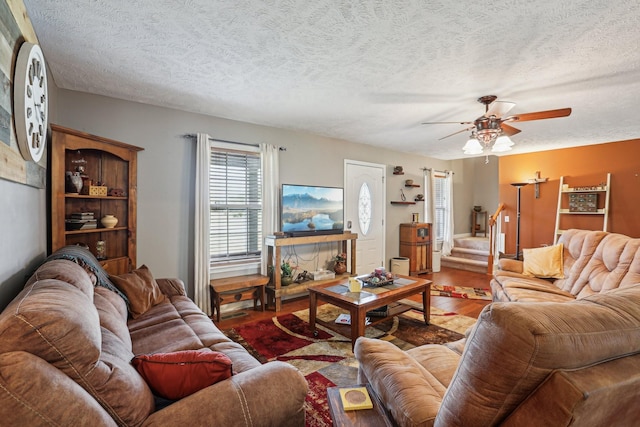 living room featuring wood-type flooring, a textured ceiling, and ceiling fan