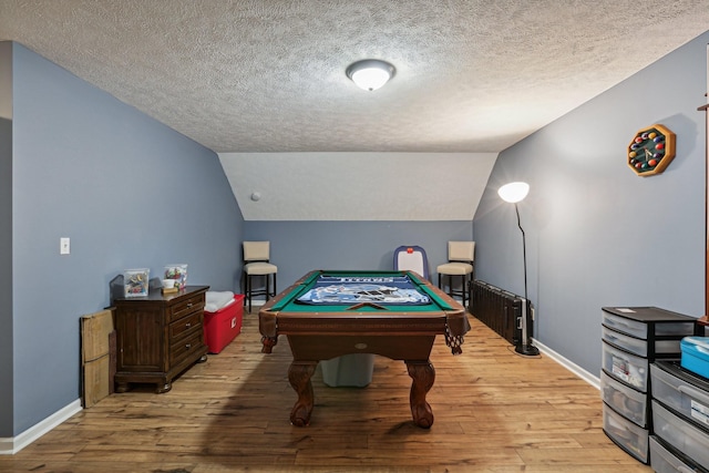 game room featuring vaulted ceiling, a textured ceiling, and light wood-type flooring