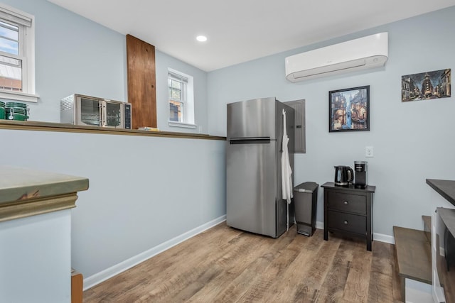 kitchen featuring hardwood / wood-style flooring, stainless steel fridge, and an AC wall unit