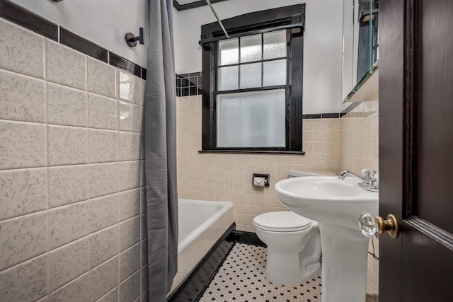 bathroom with tile patterned flooring, tile walls, shower / bathtub combination with curtain, and toilet