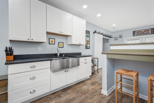 kitchen with sink, hardwood / wood-style flooring, a barn door, and white cabinets