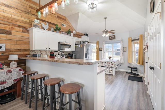 kitchen with white cabinetry, appliances with stainless steel finishes, a breakfast bar, and kitchen peninsula