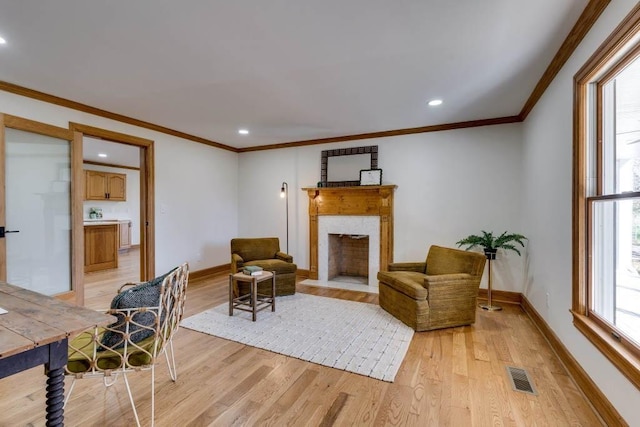 living room featuring crown molding, a high end fireplace, and light wood-type flooring