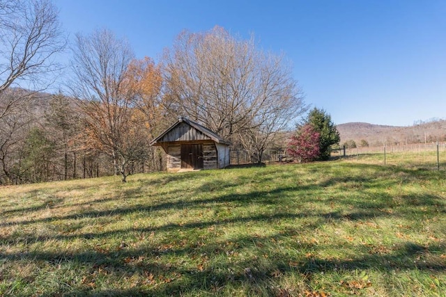 view of yard featuring an outdoor structure, a mountain view, and a rural view