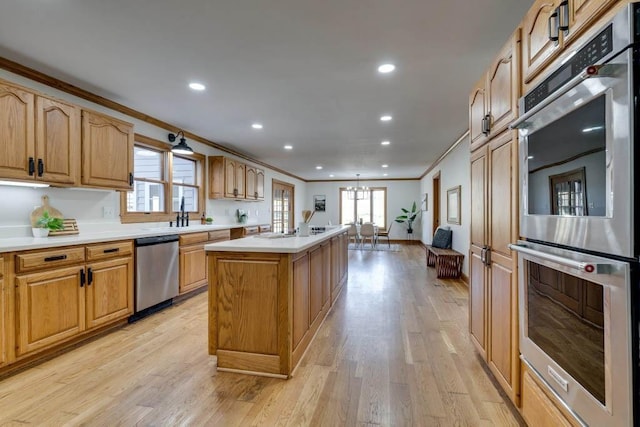 kitchen with ornamental molding, a center island, a notable chandelier, stainless steel appliances, and light wood-type flooring