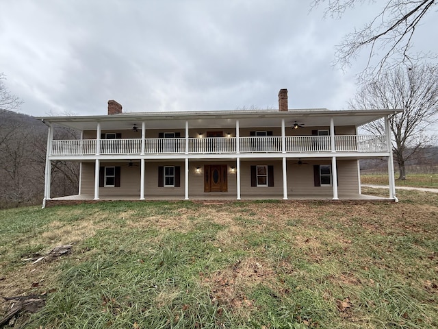 rear view of property featuring ceiling fan, a patio, and a lawn