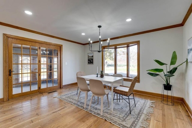 dining space with ornamental molding, a notable chandelier, light hardwood / wood-style floors, and french doors