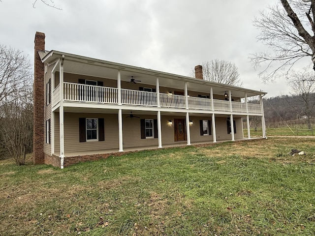 back of house featuring a balcony, ceiling fan, and a lawn