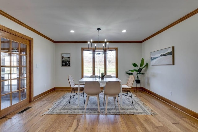 dining area featuring a notable chandelier, ornamental molding, and light wood-type flooring