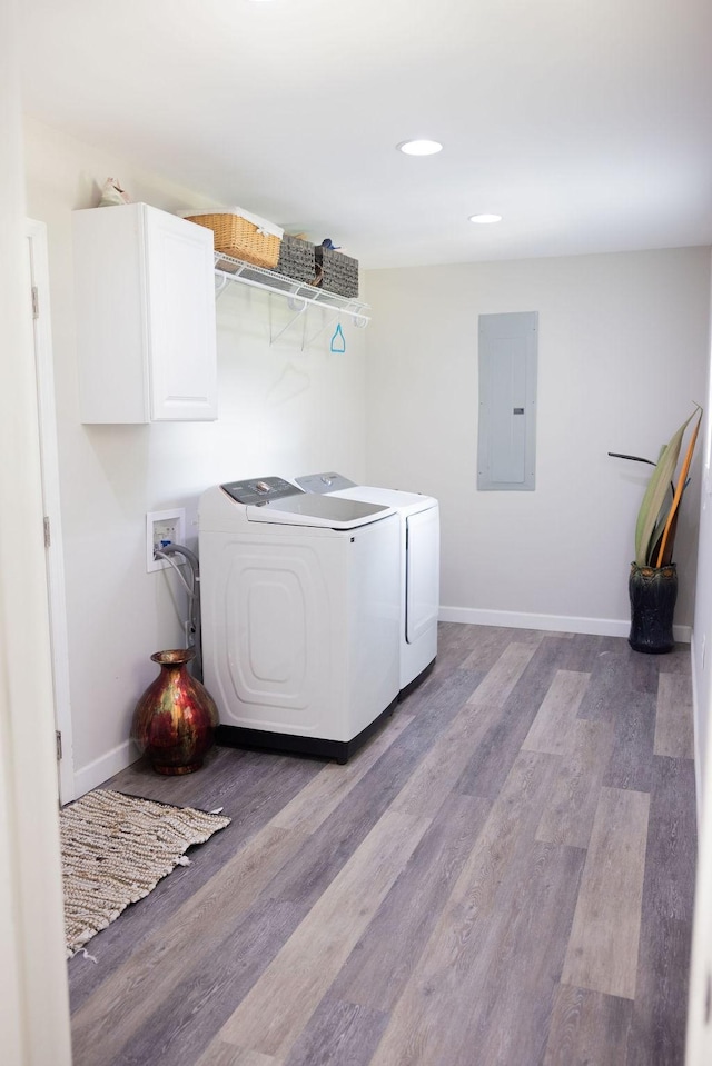 laundry area featuring cabinets, electric panel, washing machine and dryer, and light hardwood / wood-style flooring