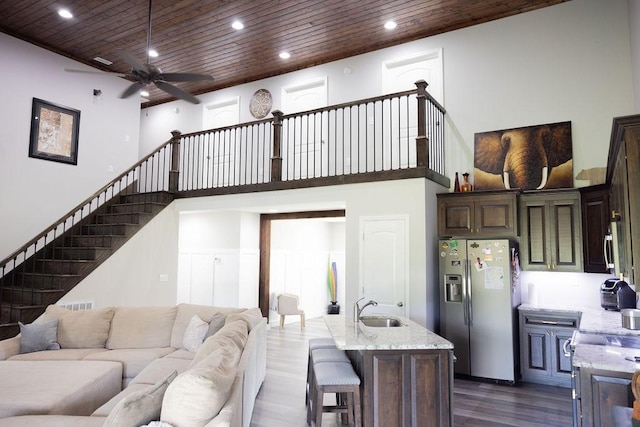 living room with a towering ceiling, dark hardwood / wood-style floors, sink, and wooden ceiling