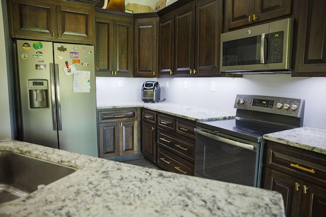 kitchen featuring dark brown cabinetry, light stone counters, and appliances with stainless steel finishes