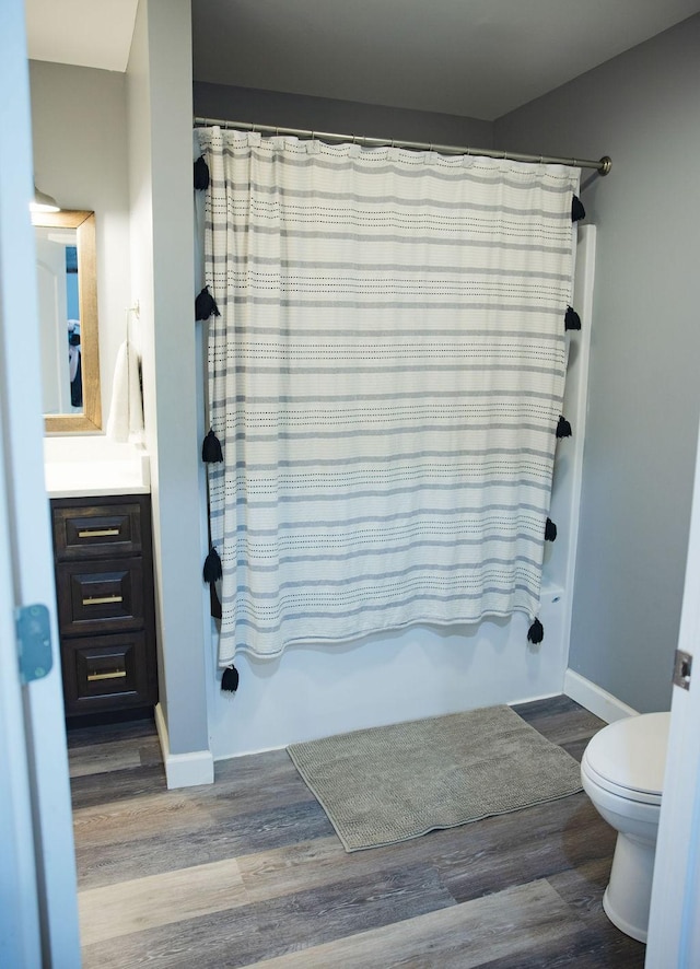 full bathroom featuring vanity, hardwood / wood-style flooring, toilet, and shower / bath combo with shower curtain