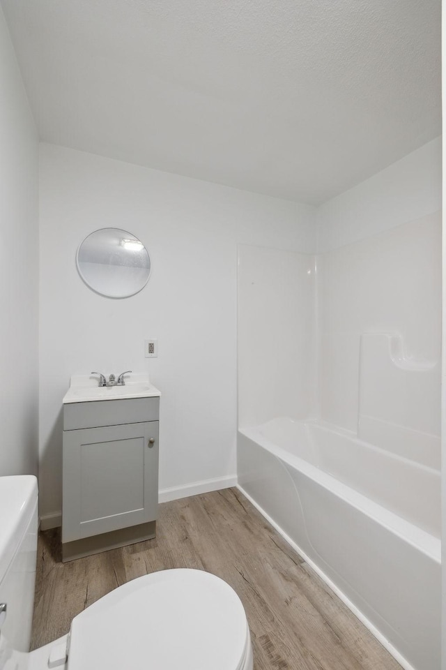 full bathroom with washtub / shower combination, vanity, toilet, and hardwood / wood-style floors