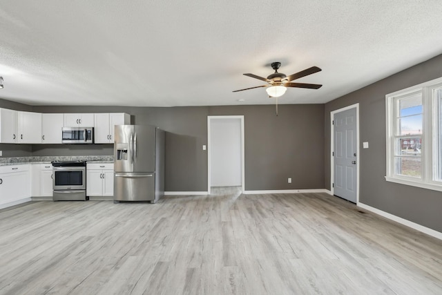 kitchen featuring white cabinetry, a textured ceiling, ceiling fan, stainless steel appliances, and light hardwood / wood-style floors