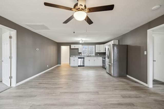 kitchen with stainless steel appliances, sink, white cabinets, and light hardwood / wood-style floors