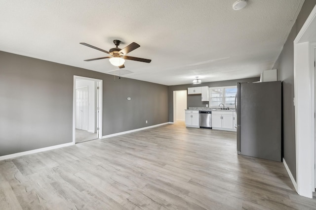 unfurnished living room featuring sink, a textured ceiling, light hardwood / wood-style flooring, and ceiling fan