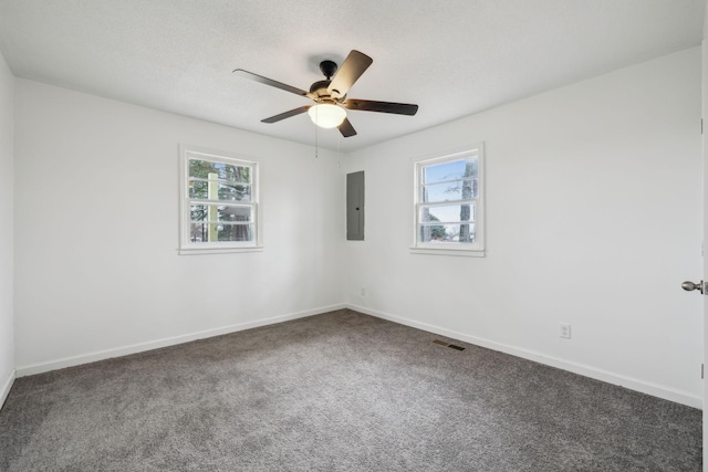 empty room with dark colored carpet, a healthy amount of sunlight, electric panel, and ceiling fan