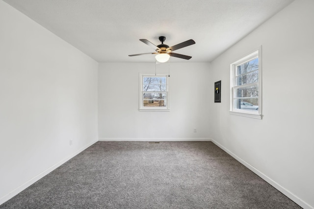 empty room featuring dark colored carpet, electric panel, and ceiling fan