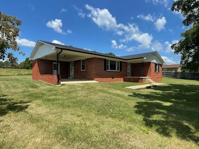 rear view of house with a patio and a lawn