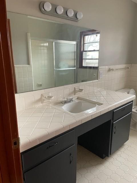 bathroom with walk in shower, vanity, toilet, and tile walls