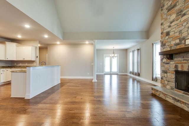 unfurnished living room featuring hardwood / wood-style floors, a fireplace, high vaulted ceiling, and a chandelier