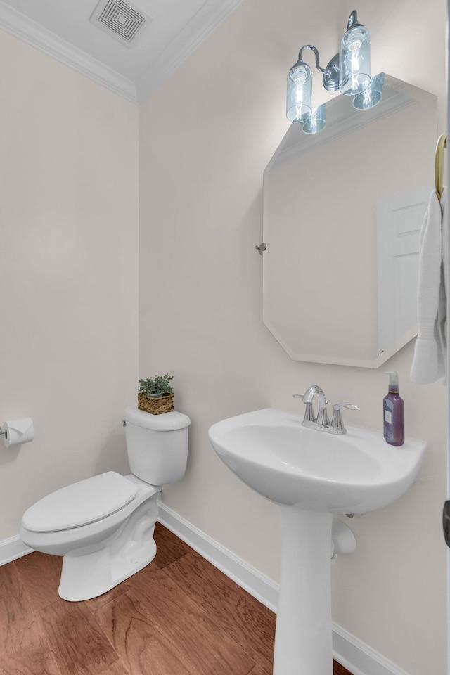 bathroom with hardwood / wood-style flooring, ornamental molding, toilet, and sink