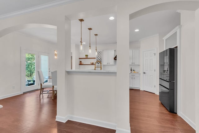 kitchen featuring crown molding, decorative light fixtures, black refrigerator, dark hardwood / wood-style floors, and white cabinets