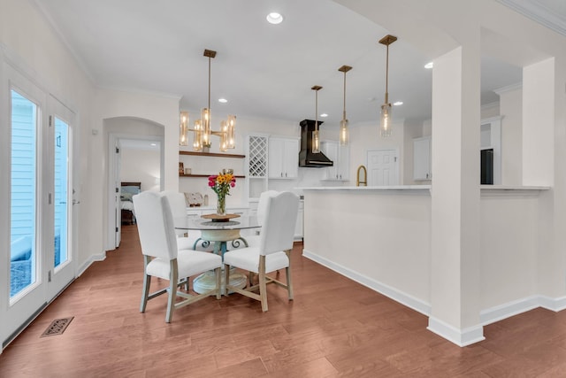 dining area featuring ornamental molding, sink, a chandelier, and light wood-type flooring