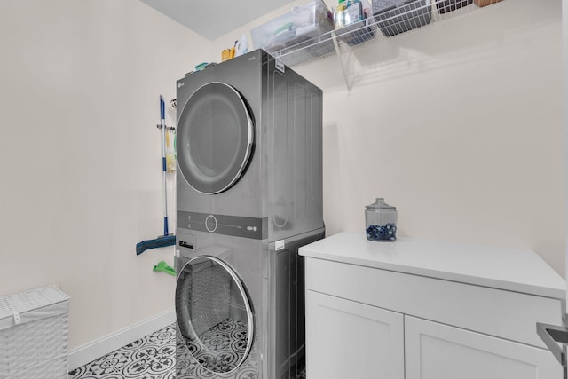 laundry area featuring cabinets, stacked washing maching and dryer, and light tile patterned floors