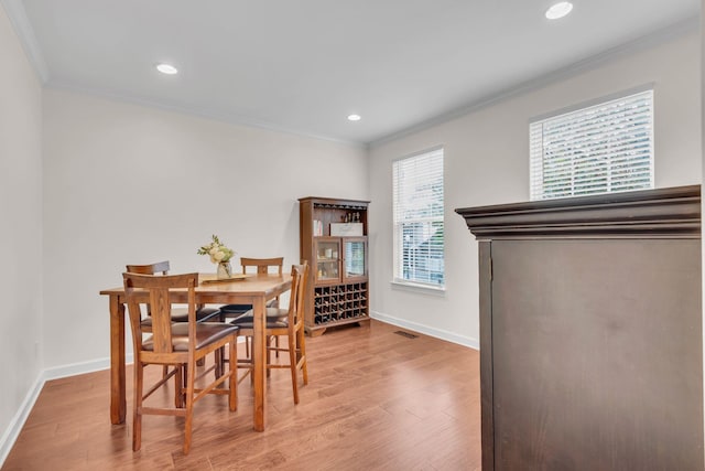 dining area with ornamental molding and light wood-type flooring