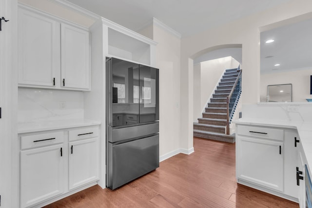 kitchen with crown molding, stainless steel fridge, light hardwood / wood-style floors, and white cabinets