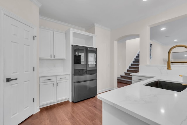 kitchen featuring ornamental molding, sink, white cabinets, and stainless steel refrigerator