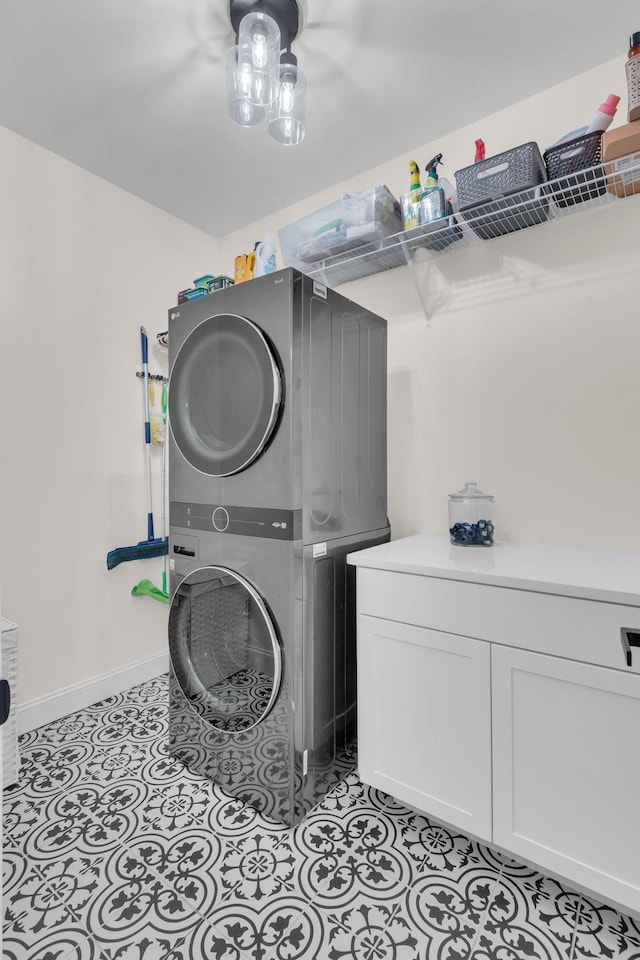 washroom with light tile patterned floors, cabinets, and stacked washer and clothes dryer