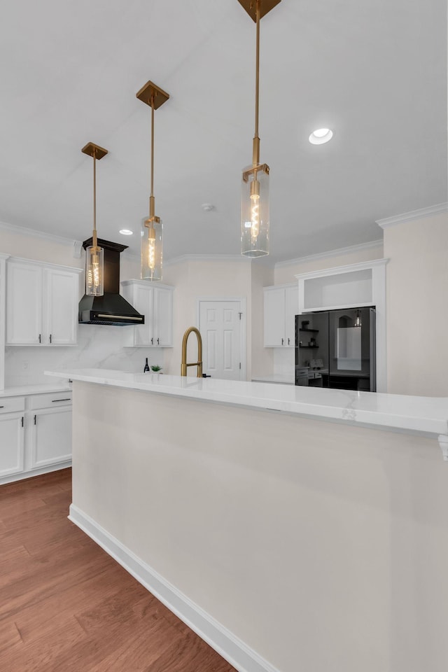 kitchen with white cabinetry, black refrigerator, ornamental molding, and custom range hood