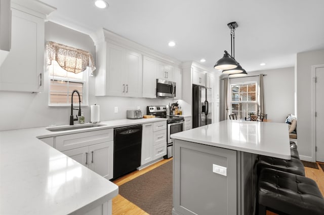 kitchen featuring white cabinetry, appliances with stainless steel finishes, sink, and a breakfast bar