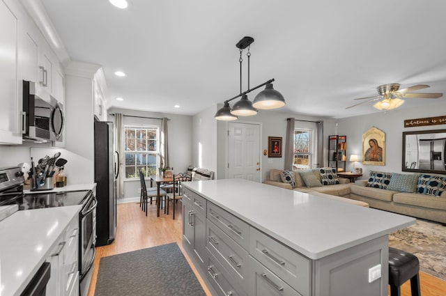 kitchen with a kitchen island, a breakfast bar, decorative light fixtures, white cabinets, and stainless steel appliances