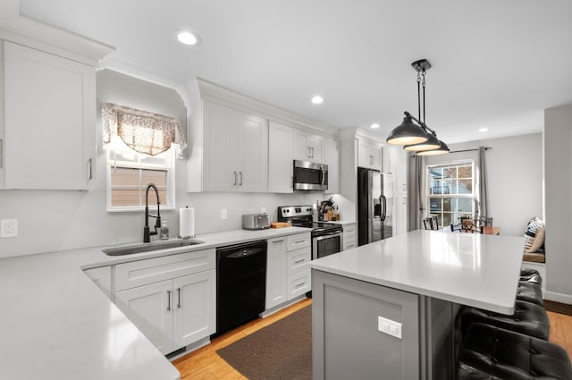 kitchen featuring appliances with stainless steel finishes, sink, white cabinets, and a kitchen breakfast bar