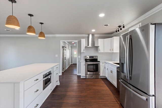 kitchen featuring appliances with stainless steel finishes, decorative light fixtures, white cabinets, crown molding, and wall chimney exhaust hood