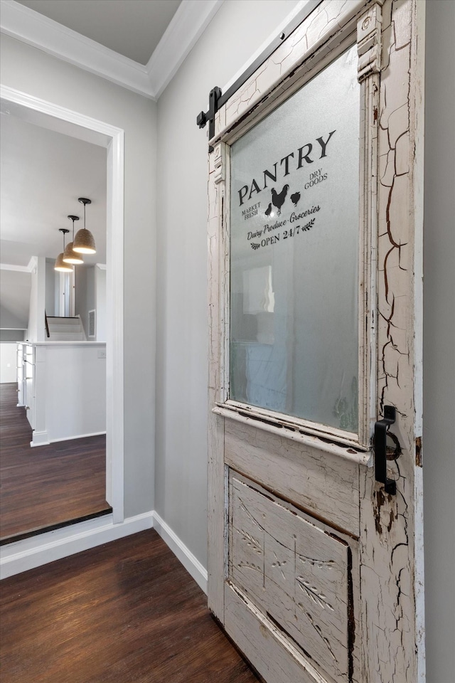 interior details with ornamental molding, a barn door, and wood-type flooring