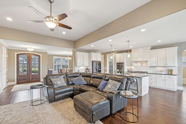 living room featuring hardwood / wood-style floors, ceiling fan with notable chandelier, ornamental molding, and french doors