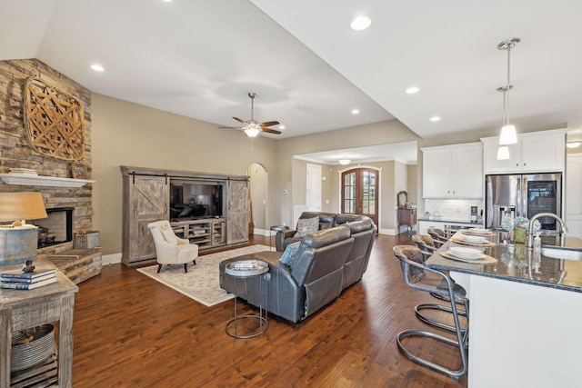 living room with dark wood-type flooring, ceiling fan, a fireplace, and sink