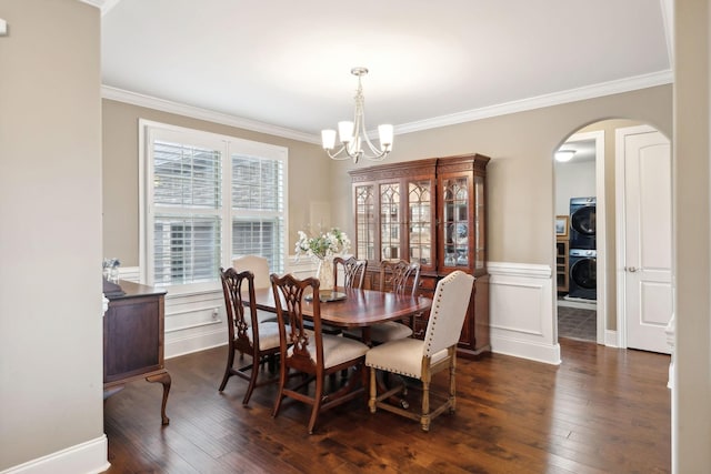 dining space with stacked washer / drying machine, a notable chandelier, dark wood-type flooring, and ornamental molding