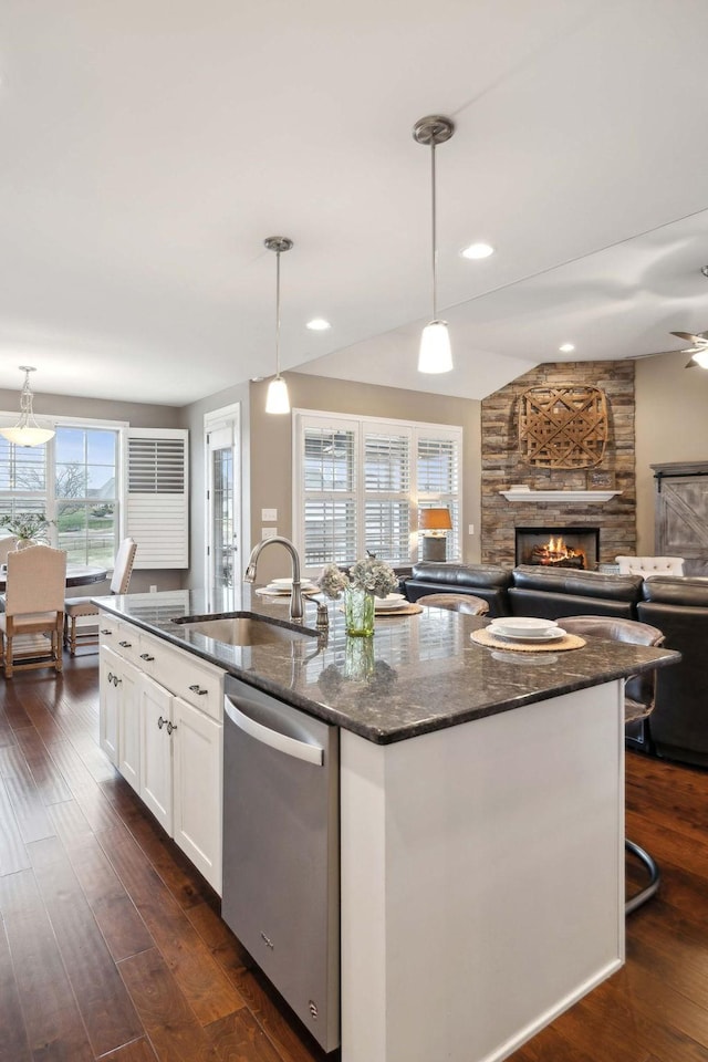 kitchen with sink, stainless steel dishwasher, pendant lighting, a kitchen island with sink, and white cabinets