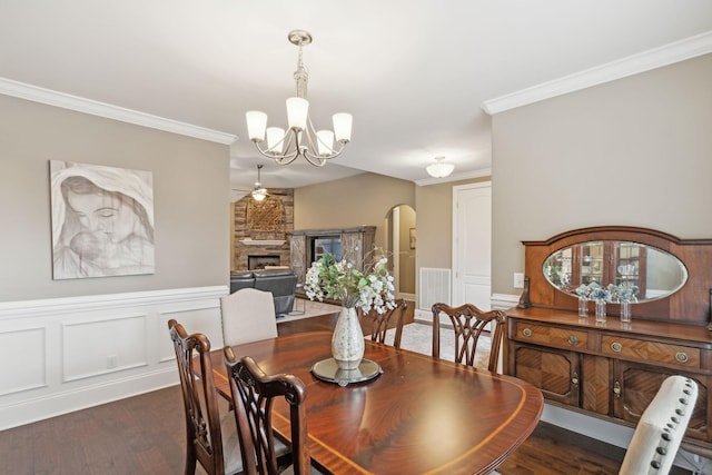 dining space with crown molding, a stone fireplace, and dark hardwood / wood-style flooring